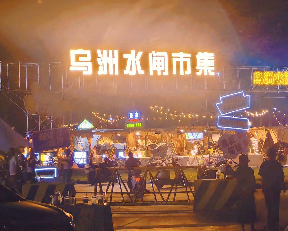 中秋夜，市集的灯牌在雾气里亮起来，帐篷和串灯连成一片暖光